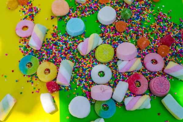 绿色背景中的口香糖和五颜六色的糖果 — 图库照片