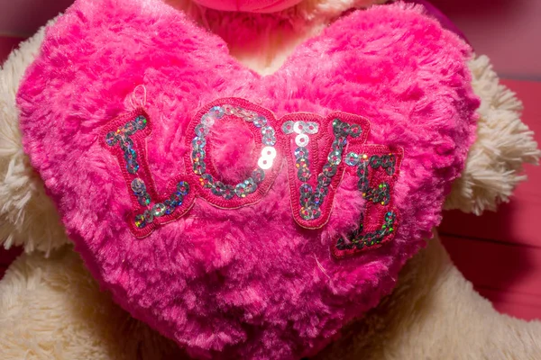 Ursinho segurando coração rosa com a palavra amor — Fotografia de Stock