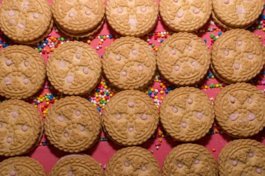 çilek aromalı kremalı kurabiye pembe üzerinde ön planda ahşap renkli