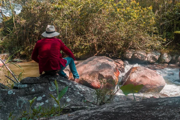 Дорослий чоловік сидить на скелі біля річки спокійно відпочиває в дуже тихій сцені — стокове фото