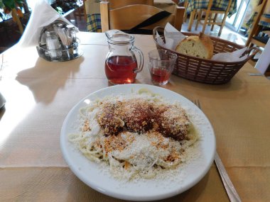 Rendelenmiş peynir, ekmek ve şarapla birlikte bir Yunan restoranında köfte ve spagetti tabağı.