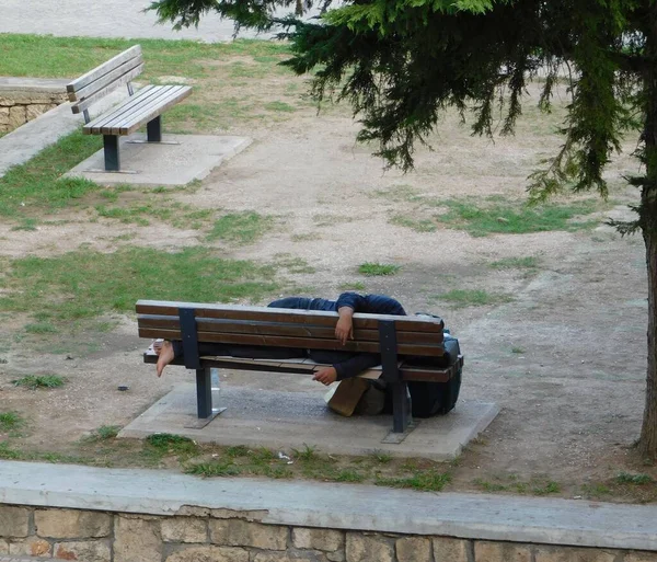 Parktaki bankta uyuyan evsiz bir adam