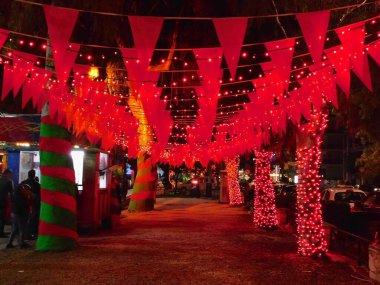 Yunanistan 'ın Glyfada kentinde Noel için kırmızı bayraklar ve ışıklarla süslenmiş bir şehir caddesi