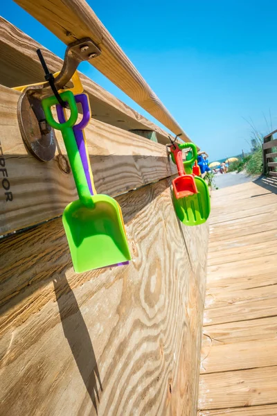 kids beach toys hanging on boardwalk entrance to the beach