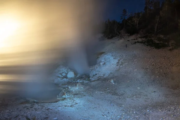 Gêiseres amarelados em erupção à noite iluminados pela luz — Fotografia de Stock