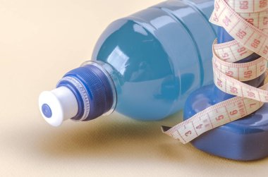 mavi dumbbells sarı santimetre ve şişe/mavi dumbbells ile santimetre ve şişe üzerinde sarı bir arka plan ile. Tonda