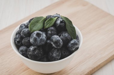 Ahşap Tepsi/taze yaban mersini ahşap tepsi üzerinde beyaz kase üzerinde beyaz kase taze yaban mersini. seçici odak. Tonda