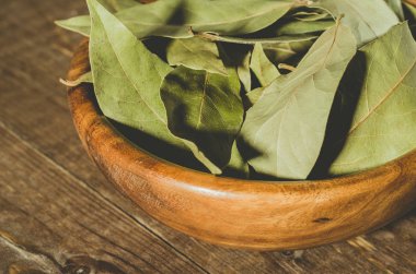 defne yaprağı ahşap arka plan üzerinde ahşap bir tabak içinde ahşap plaka/defne yaprağı. Yakın çekim