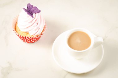 kapuçino beyaz Kupası ve kelebek/kapuçino beyaz fincan taze pasta ve beyaz mermer zemin üzerinde kelebek ile taze pasta. Üstten görünüm