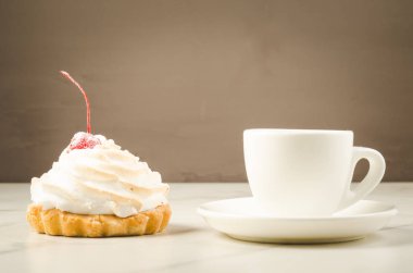 kapuçino beyaz Kupası ve taze kek kiraz/kapuçino beyaz Kupası ile ve gri arka plan üzerinde kiraz ile taze pasta.