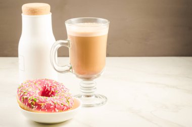 Kahve molası: cappuccino, taze şekerli pembe çörek ve beyaz şişe/kahve molası: cappuccino, taze şekerli pembe çörek ve beyaz şişe. Seçici odak ve boşaltmak