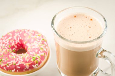 Beyaz arka plan üzerinde taze şekerli pembe çörek ile taze şekerli pembe çörek/kahve molası ile kahve molası. Yakın çekim