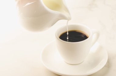 süt kahve kahve fincanı beyaz bir arka plan üzerinde beyaz bardak/süt eklenir eklenir. Seçici odak