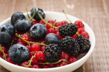 bereket beyaz bir kase çilek / ahşap bir yüzey üzerinde beyaz bir kase çilek bereket. Seçici focu