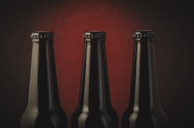 Üç şişe bira karanlık bir arka plan üzerinde kırmızı ışık/üç siyah şişe bira kırmızı ışık ile karanlık bir arka plan üzerinde siyah. Seçici odak