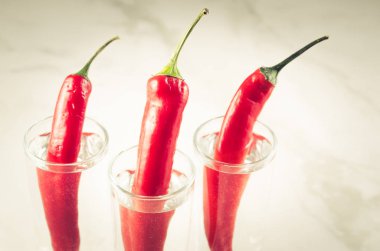 Votka ve kırmızı biber pepperthree kadeh votka ve kırmızı biber biber beyaz mermer zemin üzerinde üç çekim. 