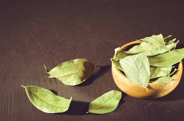 bay leaf in a wooden bowl/bay leaf in a wooden bowl on a black stone background. Copy space