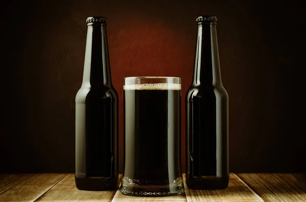 black bottle and glass beer on a red background/black bottle and glass beer on a red background of a wooden shelf