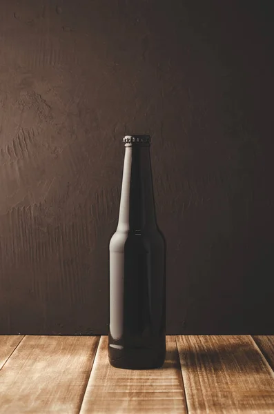black bottle of beer on a dark background/black bottle of beer on a dark background of a wooden shelf