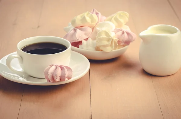 creamer, cup with coffee and meringue/creamer, cup with coffee and meringue on a wooden table