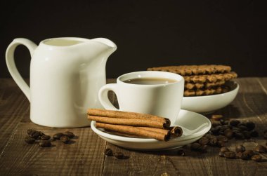 ahşap bir zemin üzerine tarçın, krema ve Çikolata Çerezler ile tarçın, krema ve Çikolata Çerezler/kahve fincanı ile kahve fincanı. Seçici focu