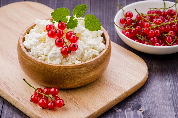 cottage cheese with red berries and mint in a wooden bowl/cottage cheese with red berries and mint in a wooden bowl. selective focus