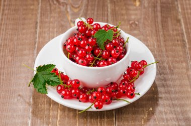 beyaz fincan kırmızı çilek/beyaz Kupası ahşap arka plan üzerinde kırmızı çilek dolu dolu. Seçici odak