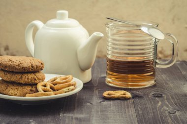 Beyaz demlik, çerezler ve yarım bardak çay/beyaz demlik, çerezler ve yarım bardak çay ahşap arka plan üzerinde