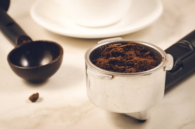 tutucu dolu ile yere kahve ve siyah kaşık/tutucu dolu çekilmiş kahve ve siyah mermer bir zemin üzerine kaşık. Seçici odak