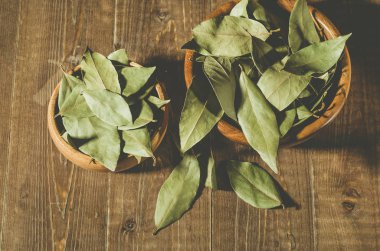 defne yaprağı bir iki ahşap kase/baharat defne yaprağı kırsal tarzı ahşap bir masa üzerinde içinde. Üstten görünüm