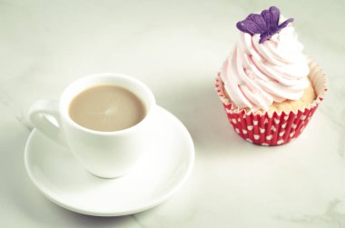 kapuçino beyaz Kupası ve kelebek/kapuçino beyaz fincan taze pasta ve beyaz mermer zemin üzerinde kelebek ile taze pasta.