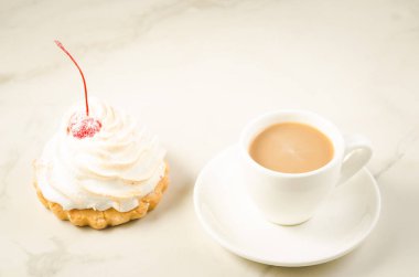 kapuçino beyaz Kupası ve taze kek kiraz/kapuçino ile Kupası ve taze kek kiraz beyaz mermer zemin üzerinde beyaz. Seçici odak