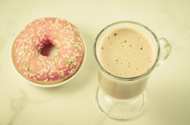 Kahve molası: cappuccino cam ile taze şekerli pembe çörek/kahve molası: cappuccino cam ile beyaz mermer zemin üzerine taze şekerli pembe çörek. En iyi görünüm ve tonda