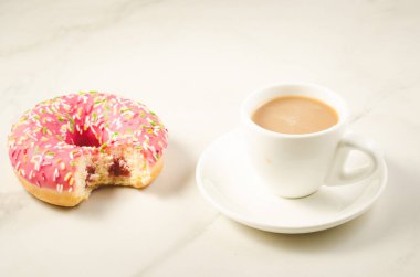 Kahve molası ısırıldı çörek/kahve molası ile beyaz mermer zemin üzerinde ısırıldı çörek ile. Seçici odak