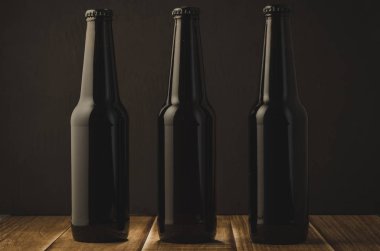 karşı ahşap bir masa üzerinde bira şişe / karanlık bir arka plan karşı ahşap bir masa üzerinde bira şişe