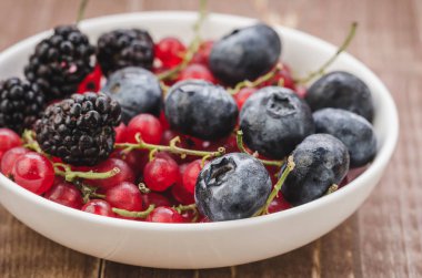 beyaz bir kase çilek / çilek ahşap arka plan üzerinde beyaz bir kase içinde bolluk. Seçici focu