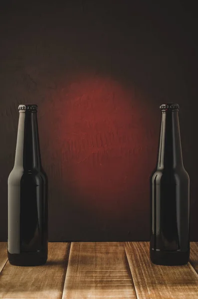 two black bottle of beer on a red background/two black bottle of beer on a red background.  Selective focus and copyspace