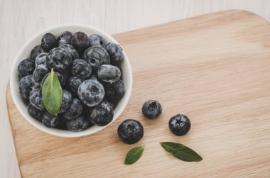 Olgun taze yaban mersini ile olgun kase/taze yaban mersini yaprak kase yapraklarda ahşap tepsi ile. Uzay kopyalayın. Üstten görünüm