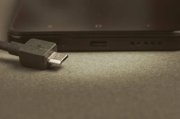 black Smartphone with charger on a gray background/black Smartphone with charger on a gray background. Close up.