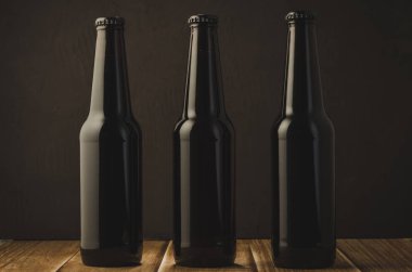 siyah şişe bira bira ahşap bir masa karanlık bir arka plan üzerinde koyu arka plan/siyah şişe karşı ahşap bir masaya. Seçici odak