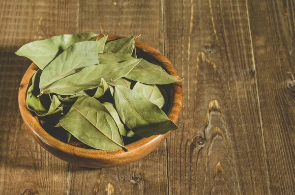 bay leaf in a wooden plate/bay leaf in a wooden plate on a wooden background. Copy space