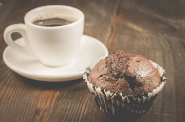 fincan sade kahve ve bir çikolatalı kek/fincan sade kahve ve koyu ahşap arka plan üzerinde çikolatalı kek. Seçici odak