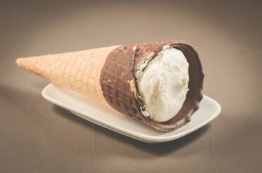 dondurma koni çikolata koyu arka plan üzerinde beyaz bir tabakta ile çikolata üzerinde beyaz plaka/Ice cream koni ile