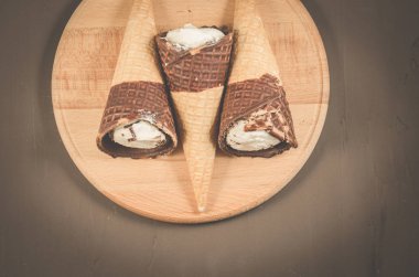 Üç dondurma koni çikolata yuvarlak ahşap destek, üstten görünüm ile içinde çikolata/üç dondurma koni ile