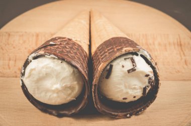 iki dondurma bir yuvarlak ahşap destek / iki dondurma koni yuvarlak ahşap arka plan, seçici odak üzerinde çikolata ile