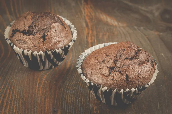 two chocolate muffins/two chocolate muffins on a dark wooden table. Selective focus