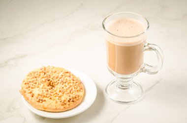 iki taze kuru bisküvi ile beyaz mermer zemin üzerine fındık ile iki taze kuru bisküvi ile fındık /cappuccino cam bardak kapuçino. Seçici odak ve boşaltmak