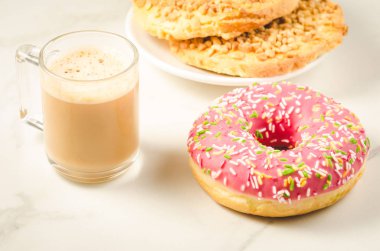 Kahve molası ile taze şekerli çörek ve taze şekerli çörek ve beyaz mermer zemin üzerinde kuru bisküvi ile Kuru bisküvi/kahve arası.