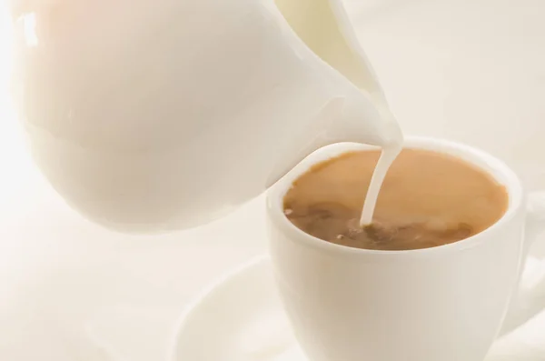 milk is added to coffee cup/milk is added to coffee cup. Selective focu