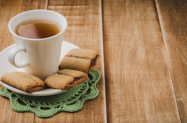 beyaz fincan çay bir ahşap arka plan/beyaz fincan çay çerezleri ahşap arka plan üzerinde kurabiyeyle ile. Kopya alanı ile.